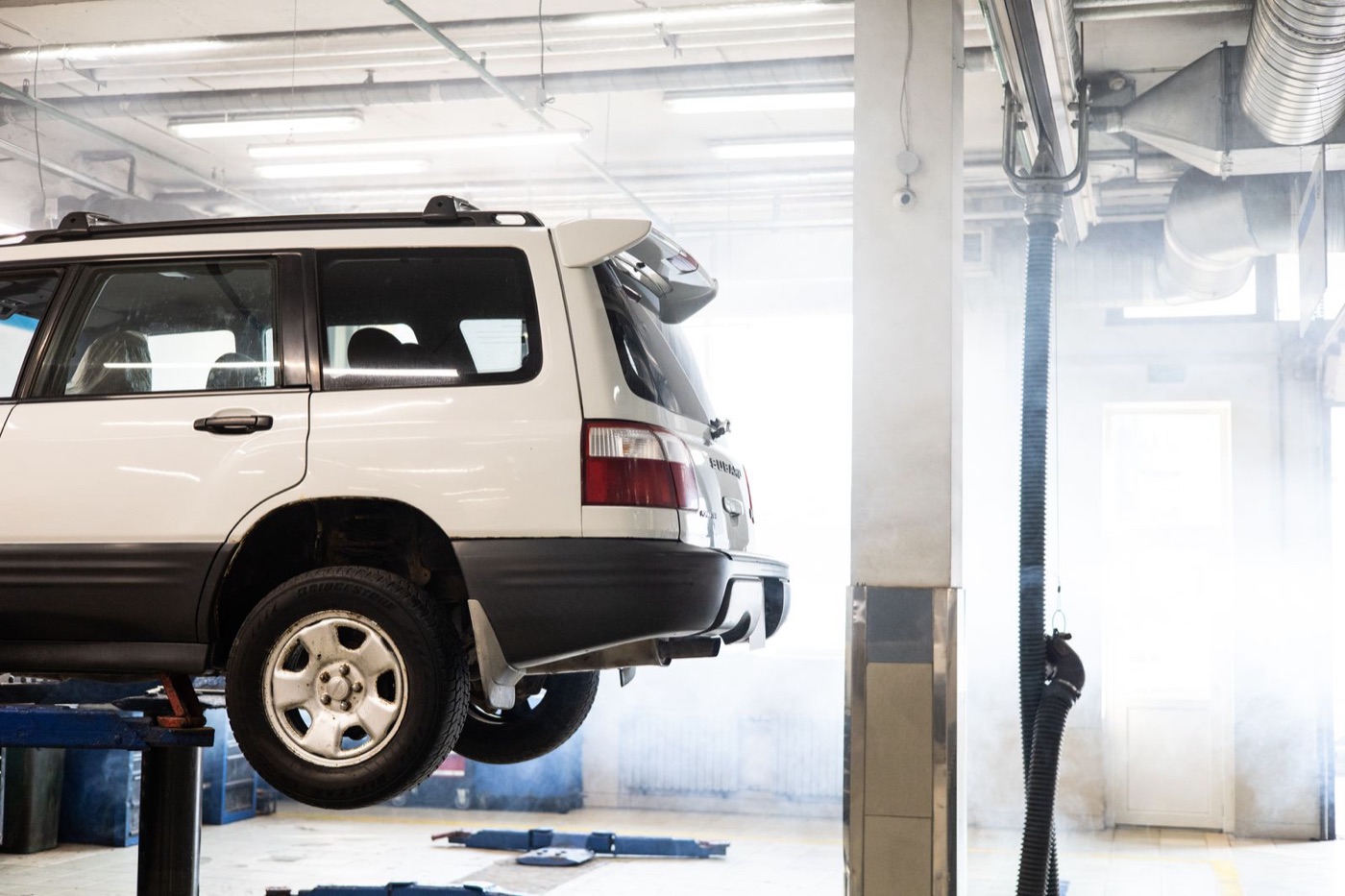 Four-post alignment rack lift with a sedan raised in a dealership service bay